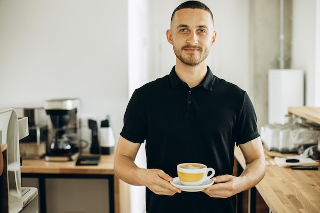 一杯のカプチーノを提供する喫茶店の男性