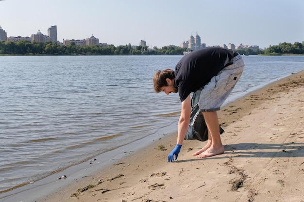 Man collecting plastic waste from a polluted beach using a garbage collector