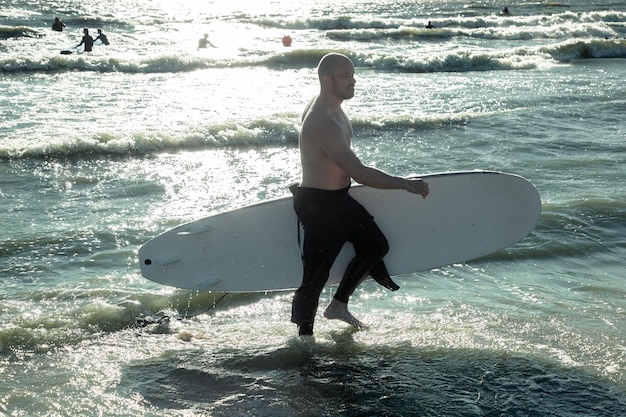 a man comes out of the sea with a surfboard