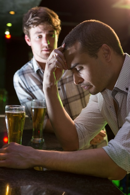 man comforting his depressed friend in bar