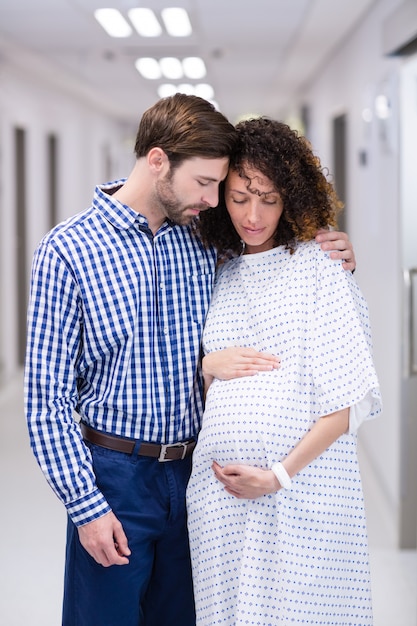 Man comforting pregnant woman in corridor