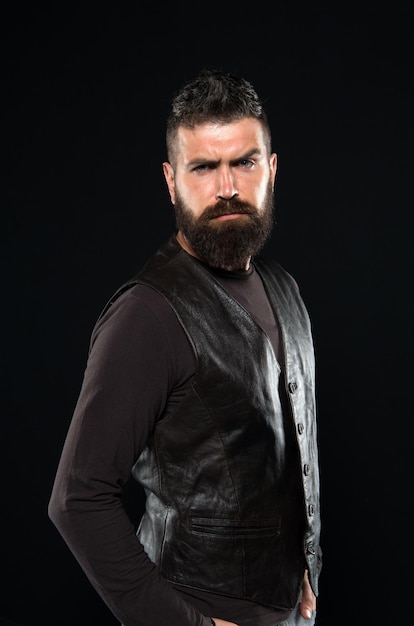 Man confident and brutal style black background Handsome face Man with beard in black leather clothes Barbershop concept Grow mustache Fashion model Strict mature face Facial hair Male face