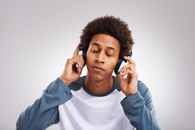 man confident and headphones in studio background for listening to music streaming podcast or playing radio black person relax and audio relief on headsets for melody sound and entertainment