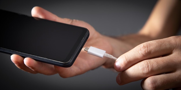 Man connecting charger cable to mobile phone