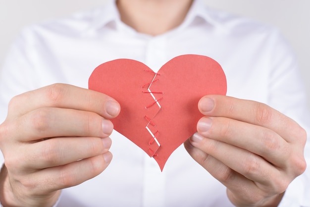 Man connecting two parts of paper heart