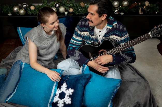 Man conquering a woman one christmas night after singing to her\
with a guitar sitting in the living room of his house