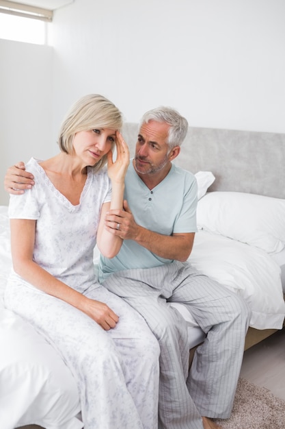 Man consoling tensed woman in bed