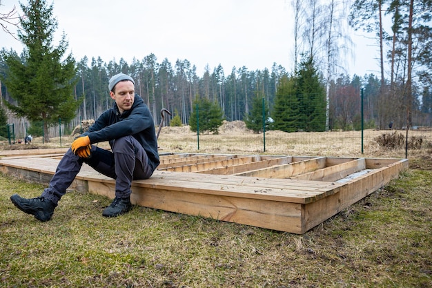 man constructing a wooden deck or terrace in a rural outdoor setting demonstrating diy carpentry skills and home improvement