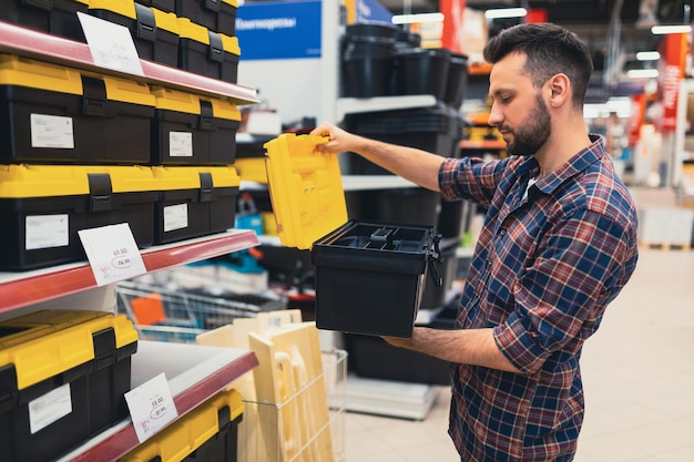 A man in a construction hypermarket chooses a case for a tool