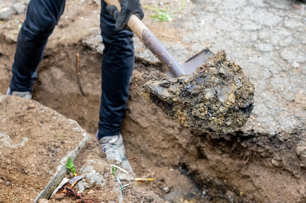 A man on a construction site digs a ditch with a shovel