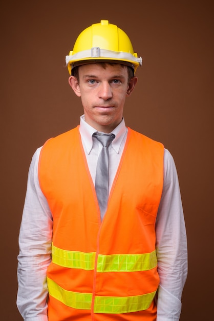 Photo man construction worker against brown wall