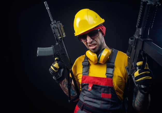 A man in a construction worker's uniform wearing a hard hat with an airsoft weapon in his hands