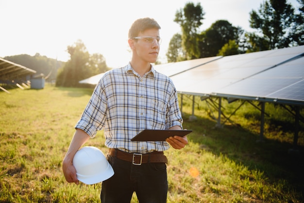 Man controleert en staat in de buurt van zonnepanelen