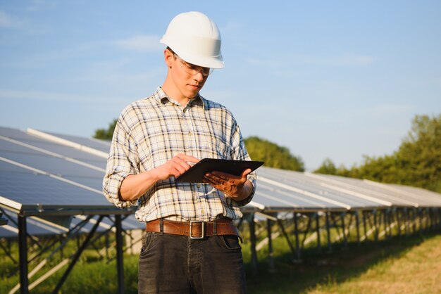 Man controleert en staat in de buurt van zonnepanelen