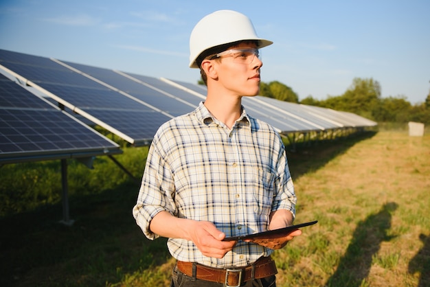 Man controleert en staat in de buurt van zonnepanelen