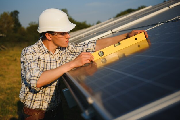 Man controleert en staat in de buurt van zonnepanelen