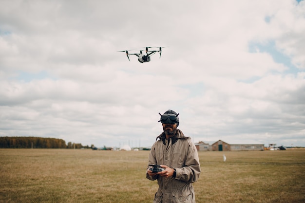 Uomo che controlla il drone quadricottero fpv con il telecomando dell'antenna per occhiali