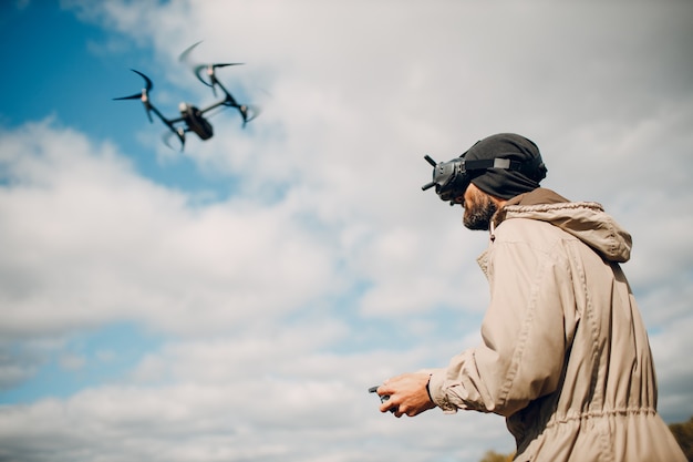 Uomo che controlla il drone quadricottero fpv con il telecomando dell'antenna per occhiali