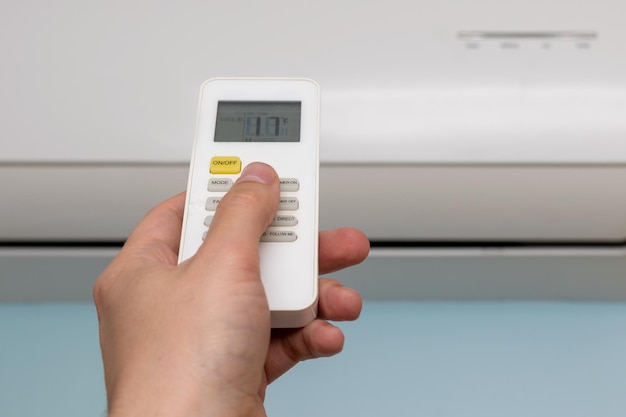 The man controls the remote control from the air conditioner for a comfortable temperature