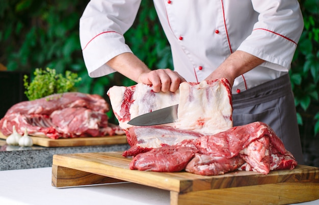 A man cook cuts meat with a knife in a restaurant.