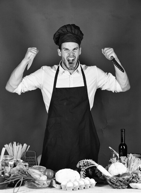 Photo man in cook hat and apron whips knives