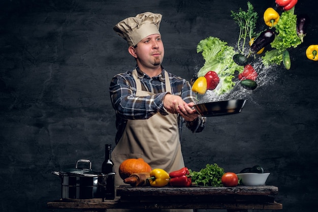 Man cook holds a pan with vegetables flying in the  air.