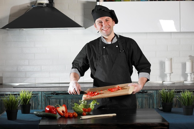 Man cook preparing food at the kitchen table of vegetables