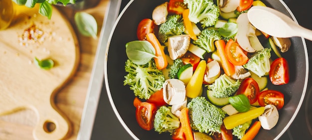 Uomo che cucina verdure fresche sulla padella