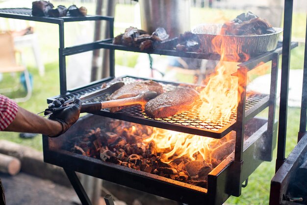 Foto un uomo che cucina la carne su una griglia con un fuoco sullo sfondo