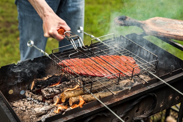 グリルバーベキューで味付けされたデンバーステーキ肉の外で調理する男