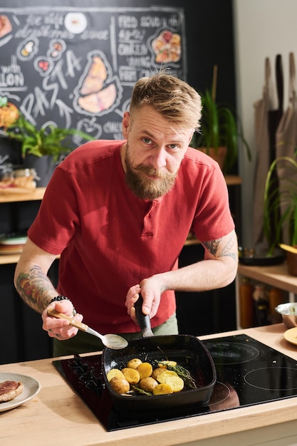 Photo man cooking potatoes in pan