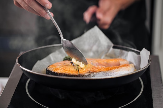 Foto uomo che cucina la bistecca di salmone arrostita su pergamena