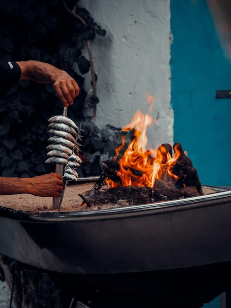 Photo man cooking sardines on fire