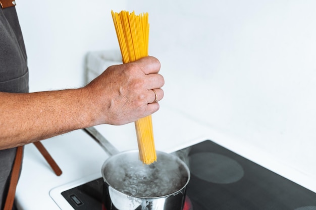 man cooking spaghetti in kitchen