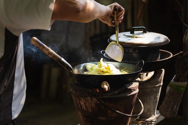 L'uomo che cucina le verdure in padella sulla stufa d'epoca che cucina con la legna da ardere cucina da solo per mangiare a casa