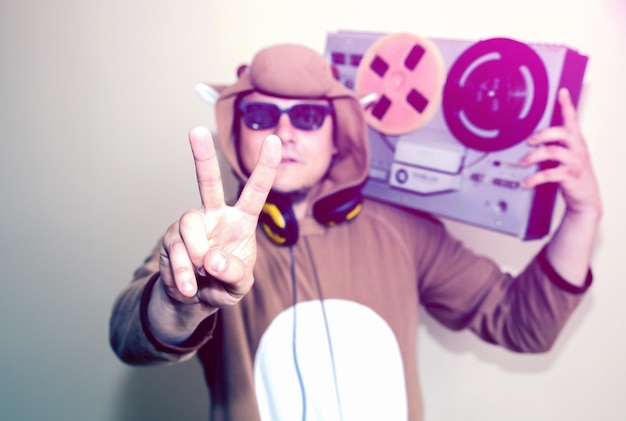 Photo man in cosplay costume of a cow with reel tape recorder. guy in the animal pyjamas sleepwear. funny photo with party ideas. disco retro music.