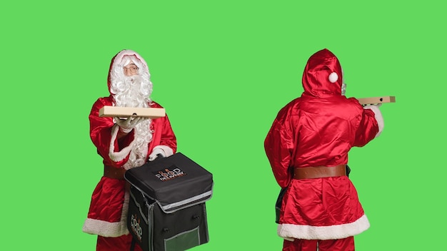 Man in costume delivering pizza in thermal backpack, portraying festive seasonal character in red suit over greenscreen background. December holiday celebration, bearded deliveryman.