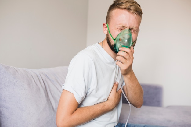 Man on couch using asthma nebulizer