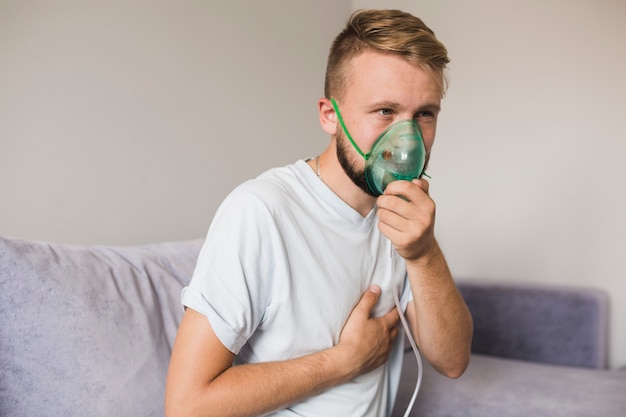 Foto uomo sul divano con nebulizzatore di asma