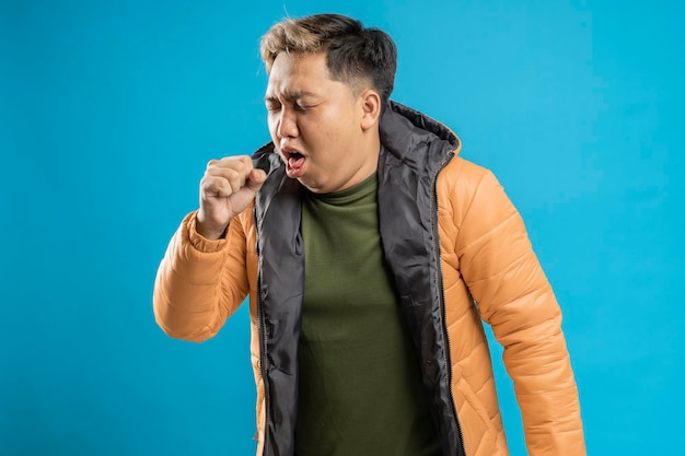 Photo man coughing into his fist isolated on a blue background