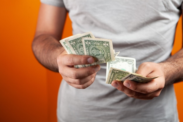 Foto l'uomo conta i soldi su sfondo arancione
