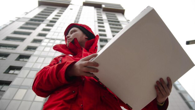 A man courier delivering pizza  looking around and waiting for the customer