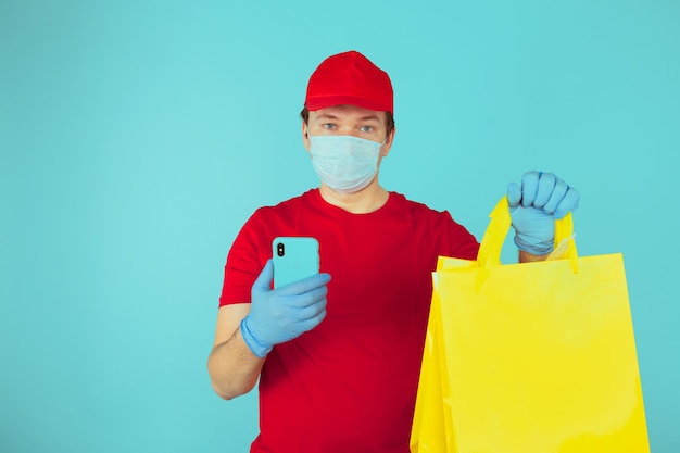 Man courier employee in the mask and red clothes with the order.