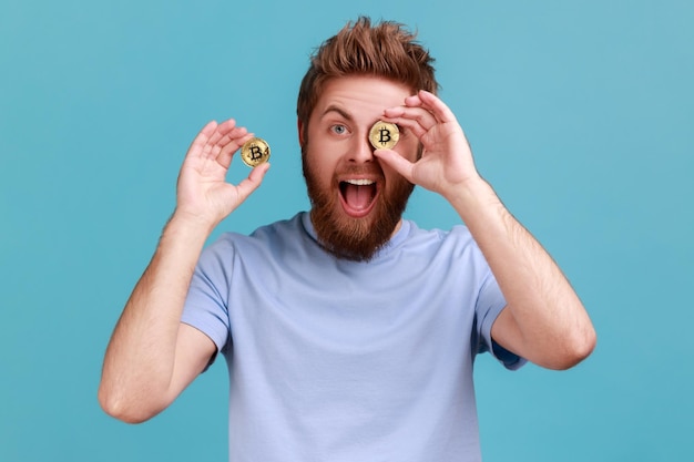 Photo man covering eye with golden btc coin and smiling to camera advertising of cryptocurrency