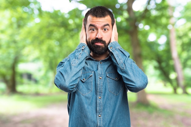 Man covering his ears on unfocused background