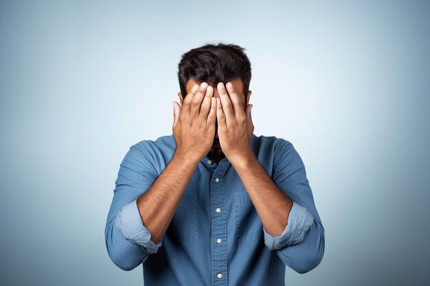 Foto un uomo che si copre il viso con le mani davanti a uno sfondo blu ai generativa