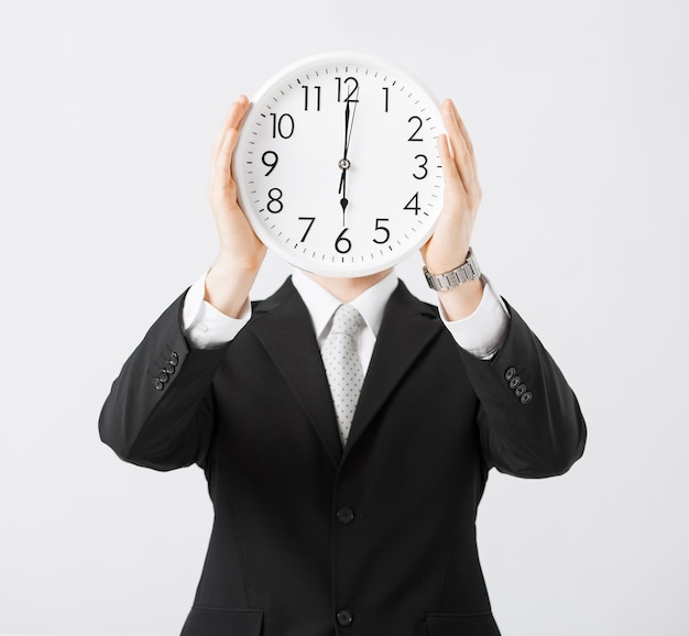 man covering his face with wall clock