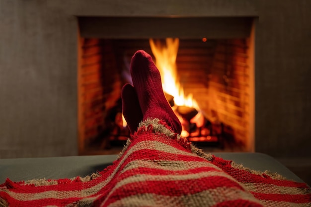 Man covering with blanket enjoys the calmness next to burning\
fireplace