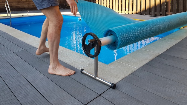 Man covers swimming pool with cover for protection