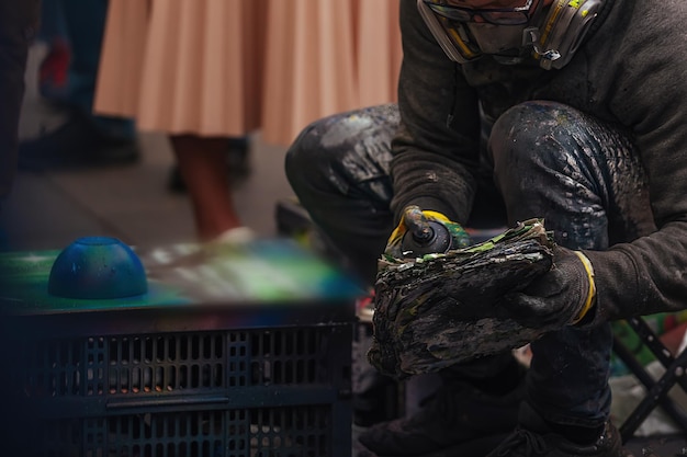 a man creates spray art with paint cans, he is surrounded by a crowd of people